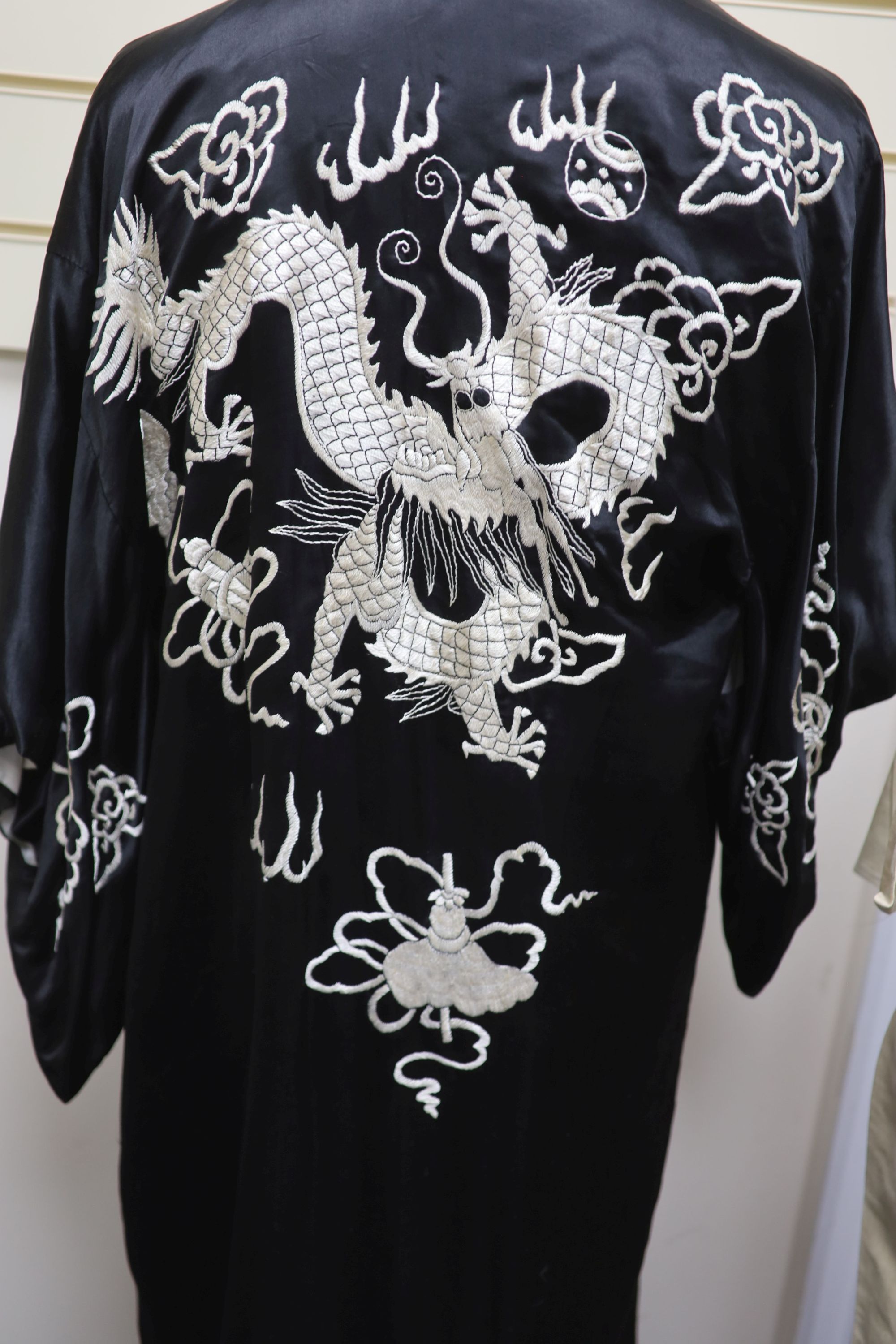 A Japanese black silk satin kimono embroidered with a white silk dragon, 133cm long and a cream silk multi-coloured embroidered dragon